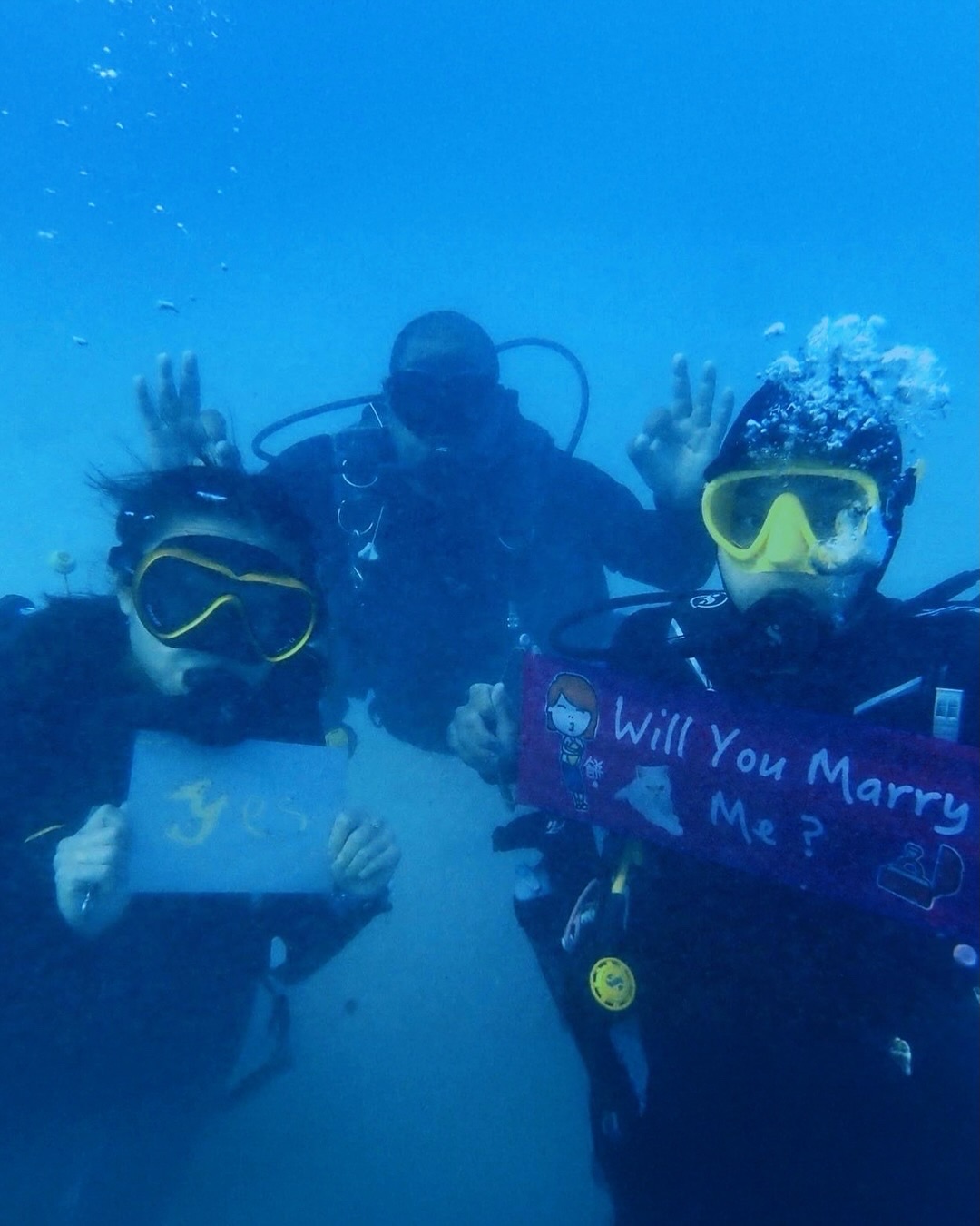 Couple diving together during an underwater proposal in Egypt