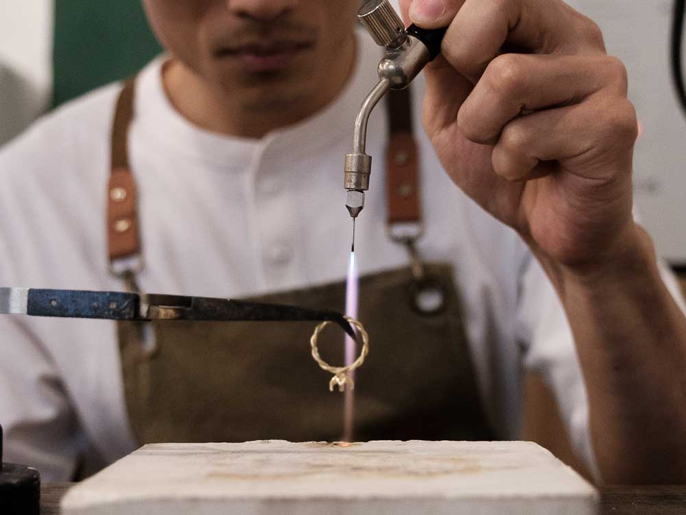 Jeweller soldering an engagement ring with a small torch